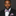 Man wearing a suit with a blue, white and red stripe patterned bow tie and pocket square on a dark background