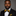 Man wearing a black suit with a yellow and black floral and stripe bow tie and pocket square against a gray background