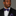 Man wearing a black suit with a purple floral bow tie and pocket square on a gray background