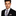 Man wearing a black suit with a patterned tie and pocket square on a white background