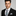 Man wearing black suit with silver and green paisley necktie and square