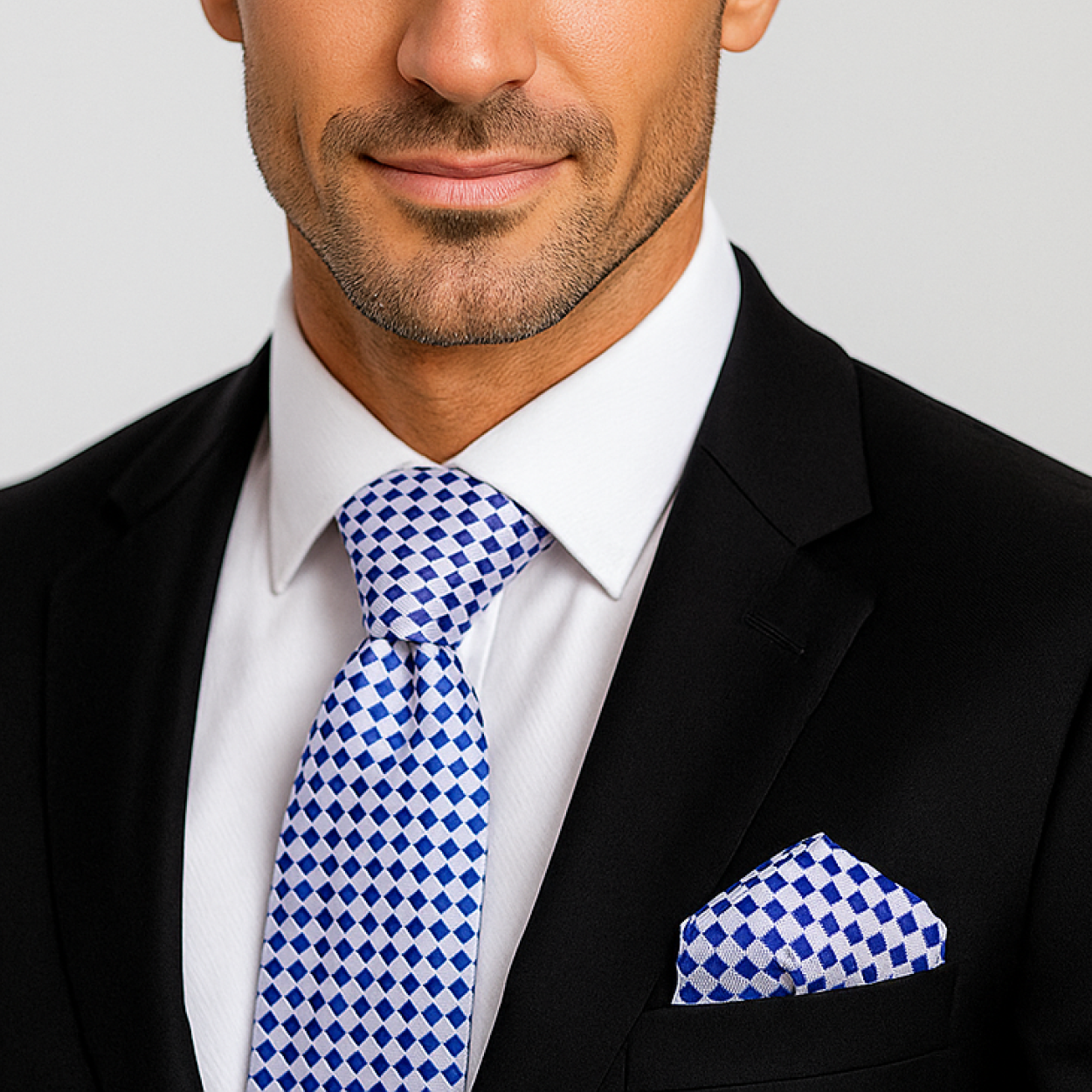 Man wearing a black suit with a blue and white checkered tie and pocket square.