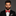 Man wearing a black suit with a red plaid bow tie on and accenting black and red stripe handkerchief on gray background