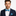 Man wearing a navy suit with a blue plaid bow tie and pocket square on a white background