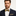 Man wearing a navy suit with a yellow and black checkered bow tie and pocket square.