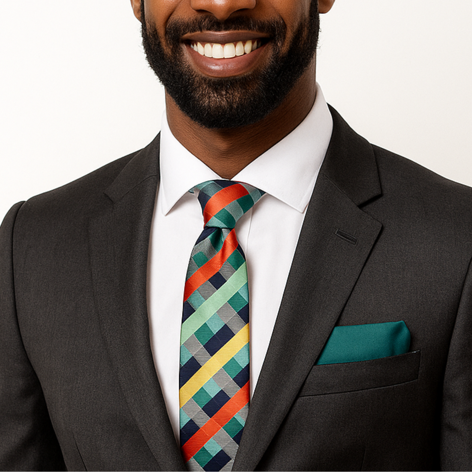 Man wearing dark grey suit with green, orange and yellow plaid necktie and green square