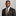 Man wearing a dark suit with a patterned tie and pocket square against a gray background