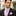 Man wearing a black suit with a pink checkered tie and pocket square.