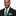 Man wearing a black suit with a green tie and pocket square on a white background