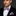 Man wearing a black suit with a pink paisley bow tie and pocket square against a dark background