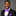 Man wearing a black suit with a purple bow tie and pocket square on a gray background