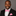 Man wearing a black suit with a pink bow tie and pocket square on a gray background