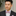 Man wearing a black suit with a pink and blue stripe bow tie and pocket square.