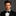 Man wearing a black tuxedo with a black bow tie against a gray background