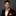 Man wearing a black suit with an orange bow tie and pocket square on a gray background