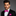 Man wearing a black suit with a pink bow tie and pocket square on a gray background