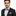 Man wearing a black suit with a purple and gray checkered bow tie and pocket square on a white background