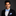 Man wearing a black tuxedo with a blue bow tie and pocket square on a dark background