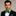 Man wearing a black suit with a green snowflake bow tie and pocket square on a gray background
