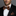 Man wearing a black suit with a leopard print bow tie and pocket square on a gray background