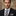 Man wearing a black suit with a Shades of White Brown Red Stripe and Flowers Necktie and Square against a blurred background