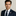 Man wearing a navy suit with an American flag pin on a plain background