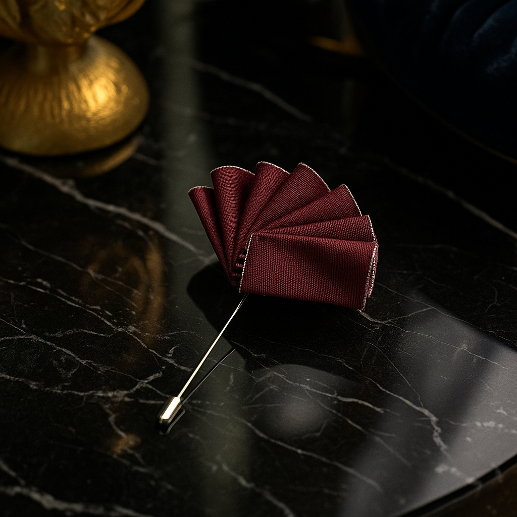 Maroon pocket square on a black marble surface with a blurred gold object in the background