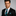 Man wearing a black suit with a Black and Light Blue Paisley and Stripe Tie and Accenting Square on a gray background