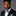 Man wearing a black suit with a blue bow tie and pocket square on a gray background