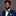 Man wearing a blue suit with a floral bow tie and pocket square on a gray background