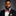Man wearing a black suit with a colorful bow tie and pocket square on a gray background