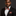 Man wearing a black suit with a colorful bow tie and pocket square on a dark background