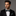 Man wearing a black suit with a Green, Brown and Grey Check Bow Tie and Pocket Square on a gray background