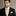 Man wearing a black suit with a Beige Check Tie and Square against a neutral background