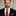 Man wearing a black suit with a A Deep Red Check Necktie, Pocket Square against a neutral background