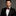 Man wearing a black suit with a Red Lines Bow Tie and Pocket Square on a gray background