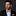 Man wearing a black suit with a colorful bow tie and pocket square on a dark background