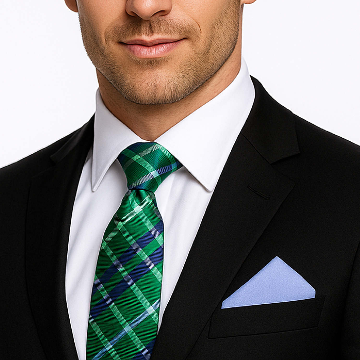 Man wearing a black suit with a green plaid tie and light blue pocket square on a white background