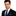 Man wearing a black suit with a blue tie and pocket square on a white background