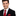 Man wearing a black suit with a red tie and pocket square on a white background