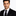 Man wearing a black suit and tie against a white background