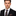 Man wearing a black suit with a colorful tie and pocket square on a white background