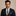Man wearing a navy suit with a patterned tie and pocket square on a beige background