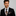 Man wearing a black suit with a colorful tie and pocket square on a gray background