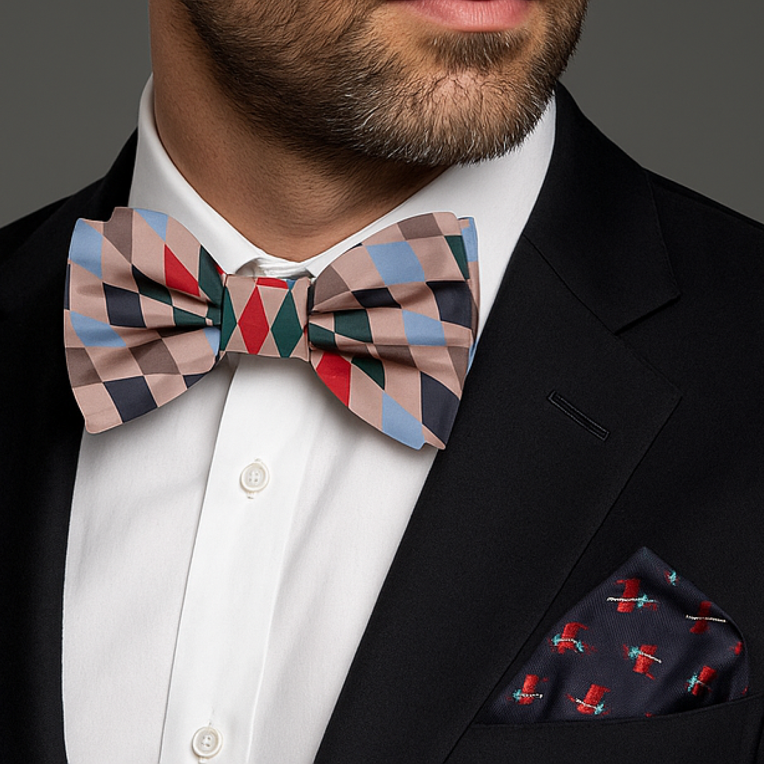 Man wearing a colorful checkered bow tie and blue reindeer pocket square.
