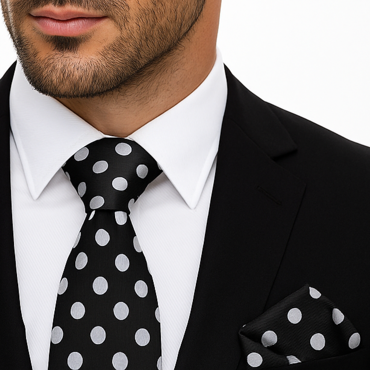 Man wearing a black suit with a white polka dot tie and pocket square.