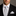 Man wearing a black suit with a white shirt, polka dot tie, and matching pocket square.