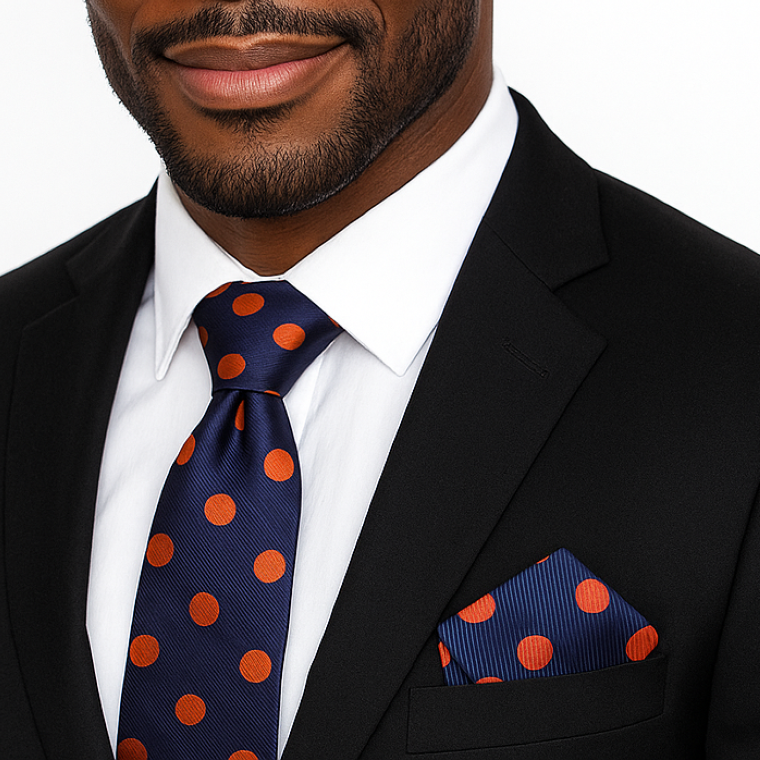 Man wearing a black suit with a blue tie and pocket square featuring orange polka dots.
