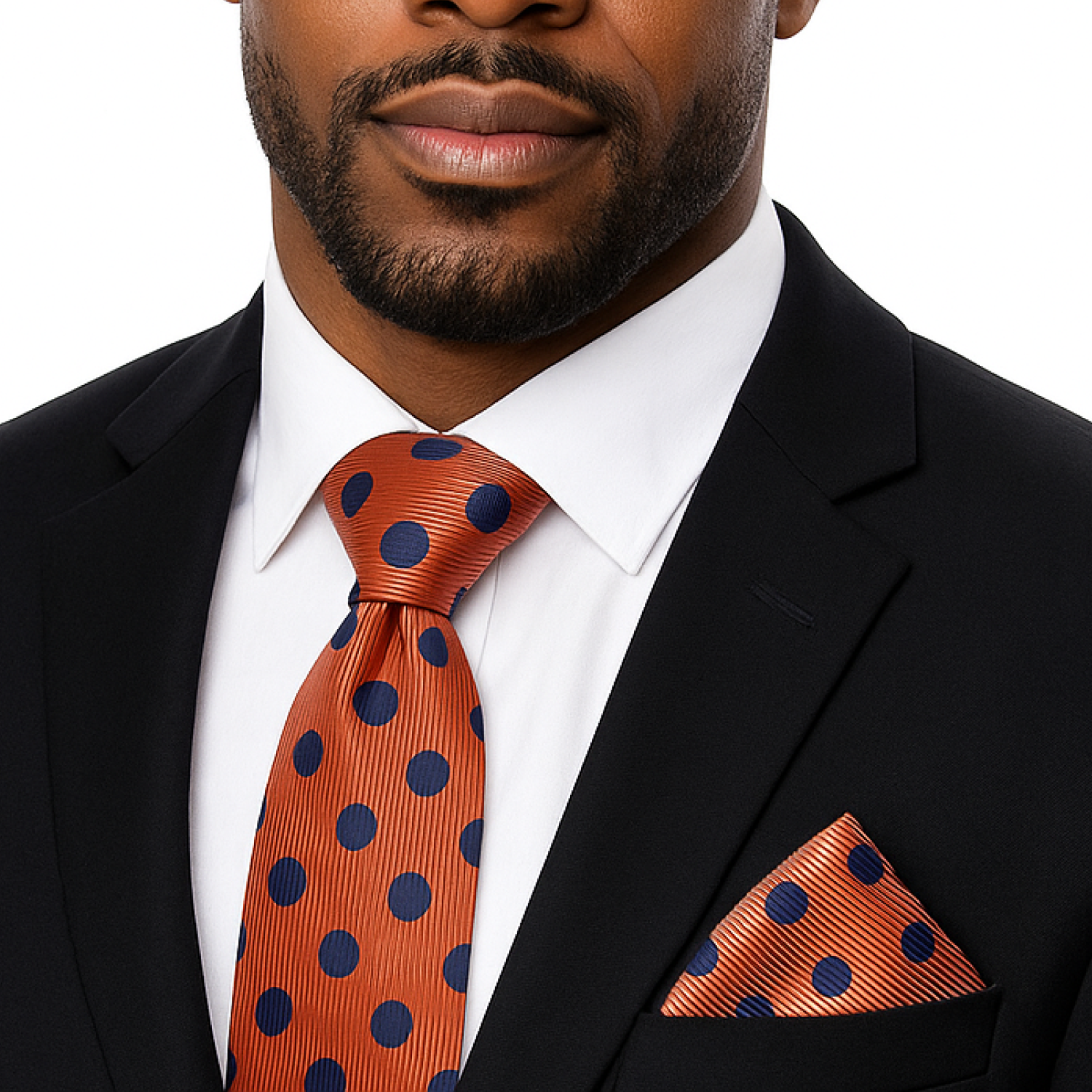 Man wearing a black suit with an orange tie and pocket square featuring blue polka dots.