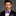 Man wearing a black suit with a colorful bow tie and pocket square on a gray background